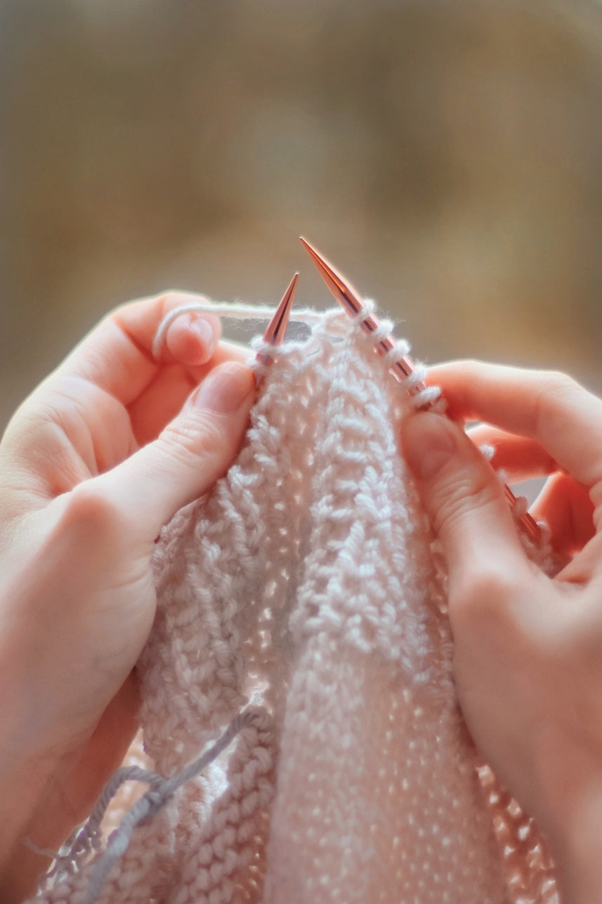 Hands demonstrating continental knitting technique with yarn held in left hand - European picker style knitting tutorial