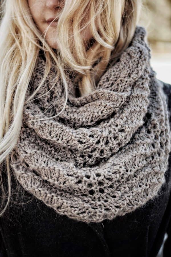 Cream cowl scarf draped on wooden hanger showing textured knit detail - Fauna knitting pattern by Darling Jadore