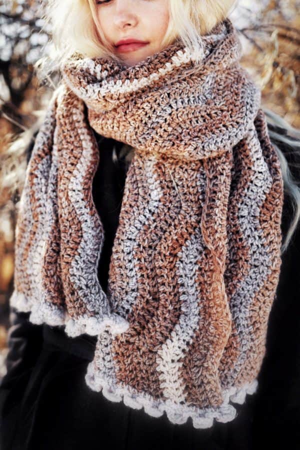 Close up of wave crochet scarf showing ripple stitch texture and bobble border in warm neutral colors