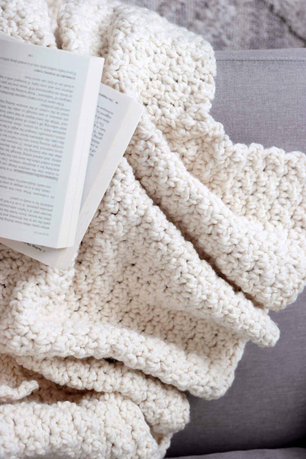 Chunky textured throw blanket crochet pattern in neutral cream yarn draped over chair