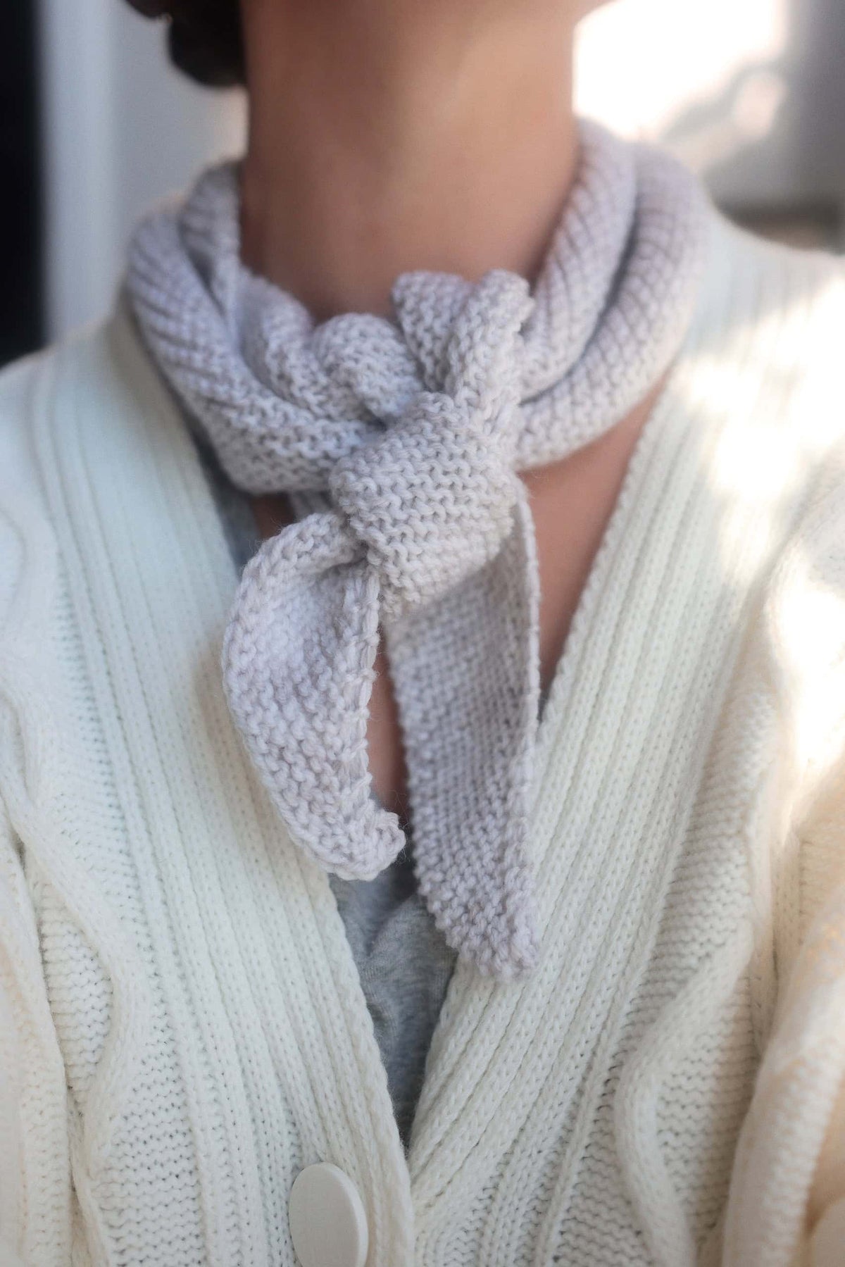Small knitted neck scarf in cream yarn draped elegantly - Sunday Scarf neckerchief pattern by Darling Jadore