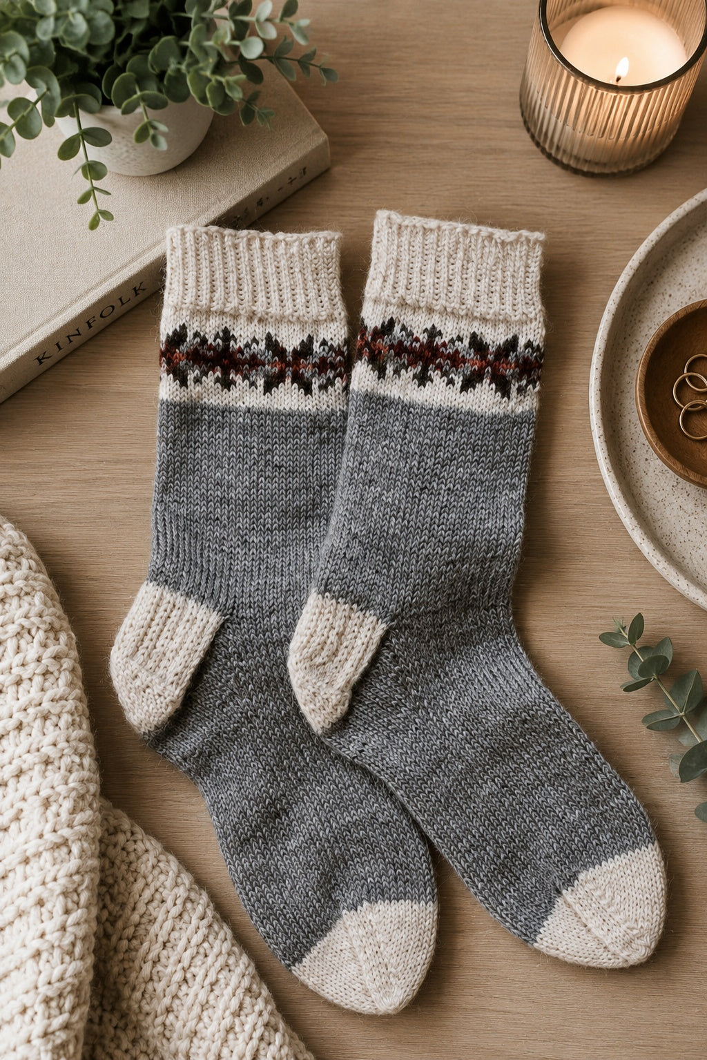Fair Isle socks with snowflake pattern knit in cream and gray yarn on wooden surface