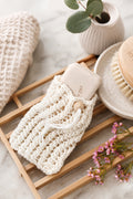 Eco-friendly knit soap saver bag with lacy stitches and drawstring closure holding bar soap
