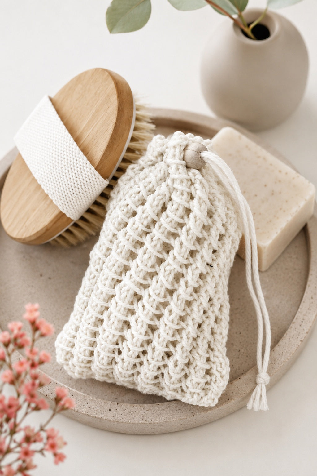 Eco-friendly knit soap saver bag with lacy stitches and drawstring closure holding bar soap