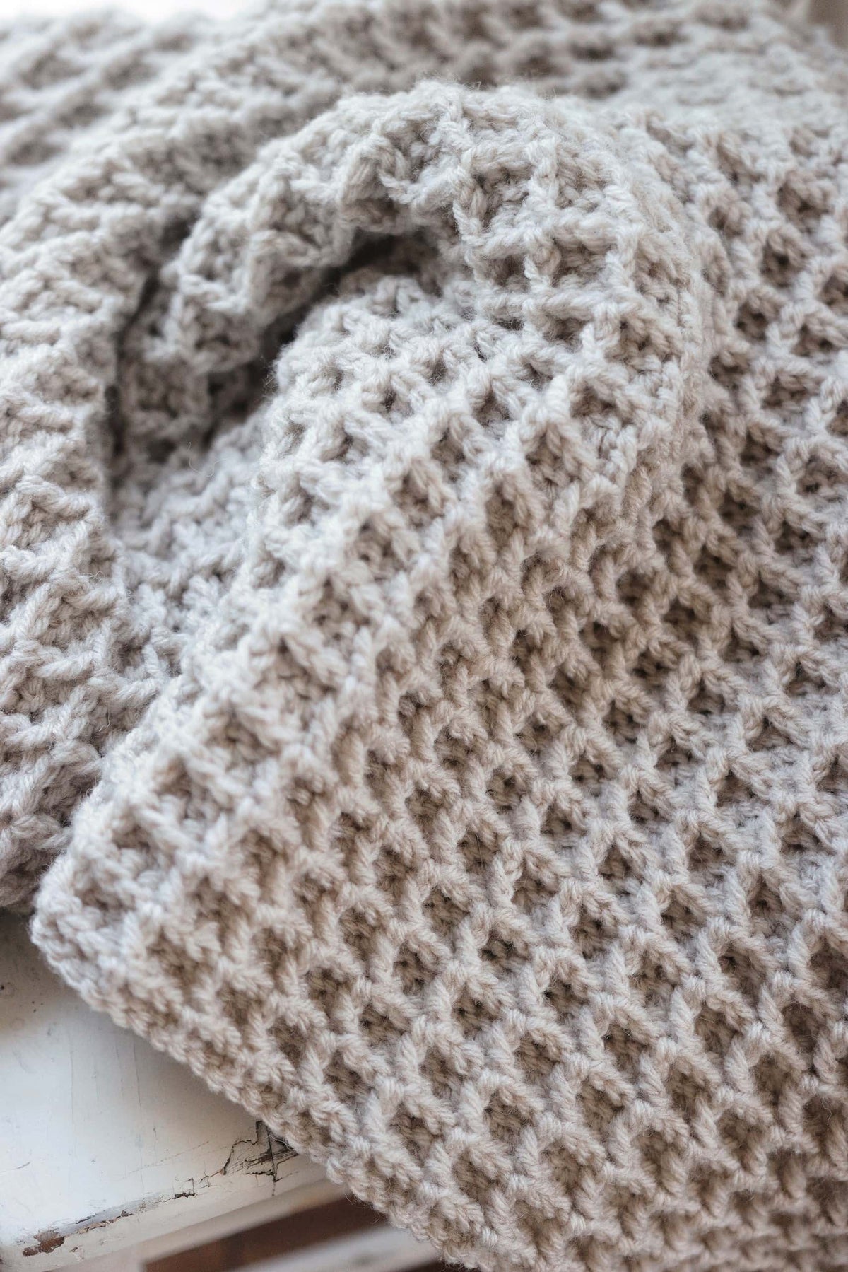 Handmade waffle stitch crochet blanket draped elegantly in neutral living space