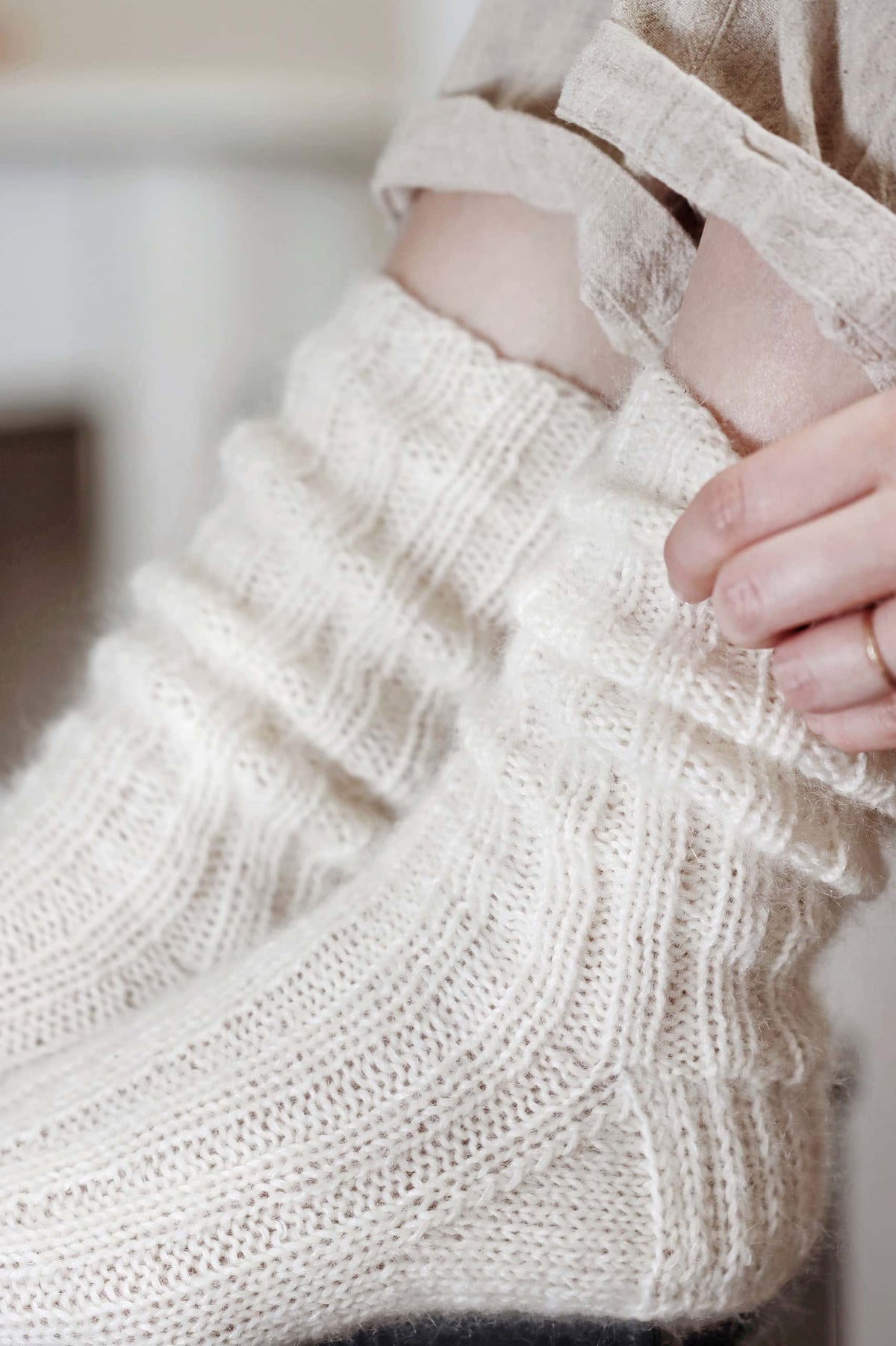 Woman wearing buttery soft cream knitted socks in cozy home setting