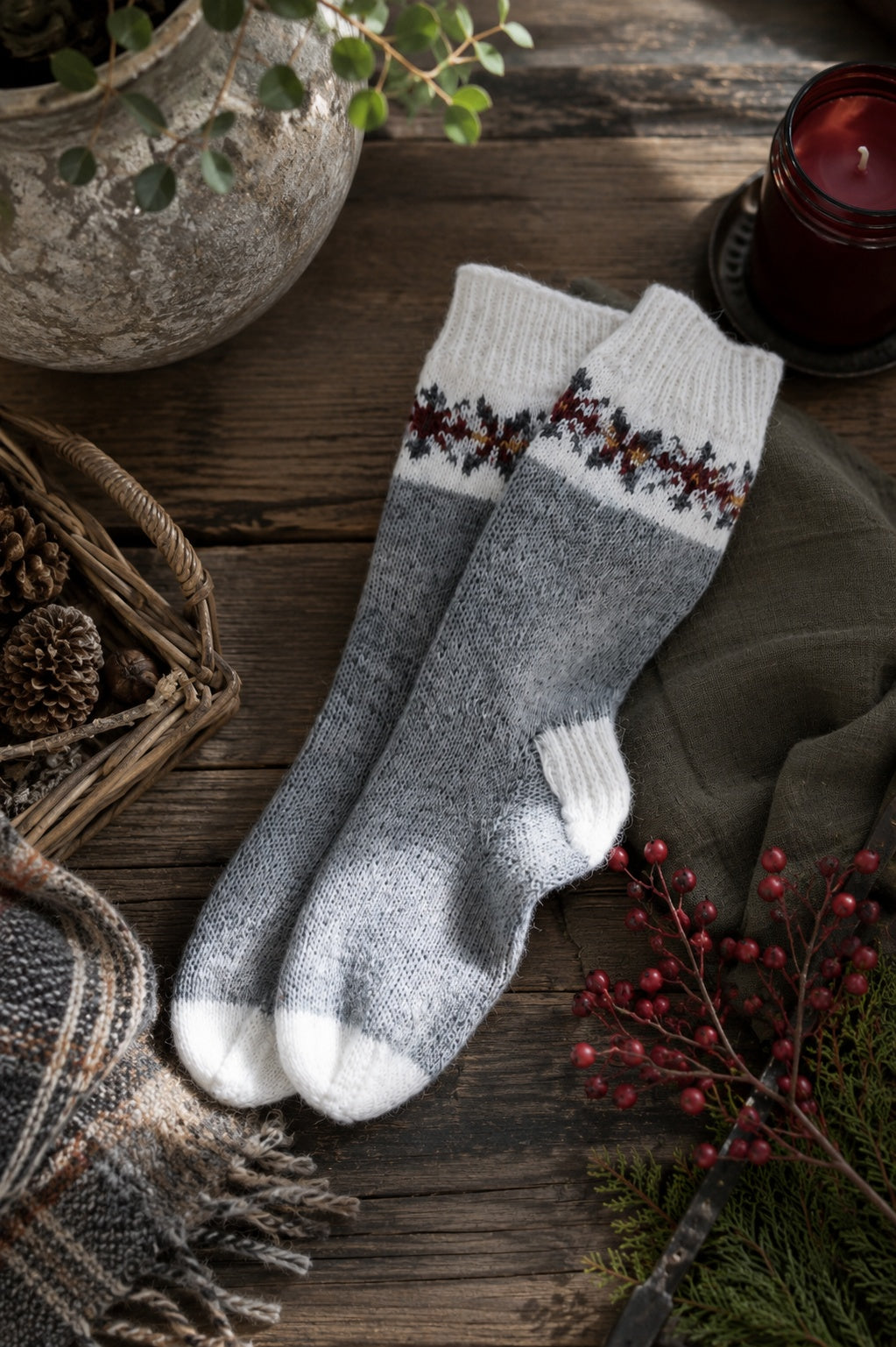 Fair Isle socks with snowflake pattern knit in cream and gray yarn on wooden surface