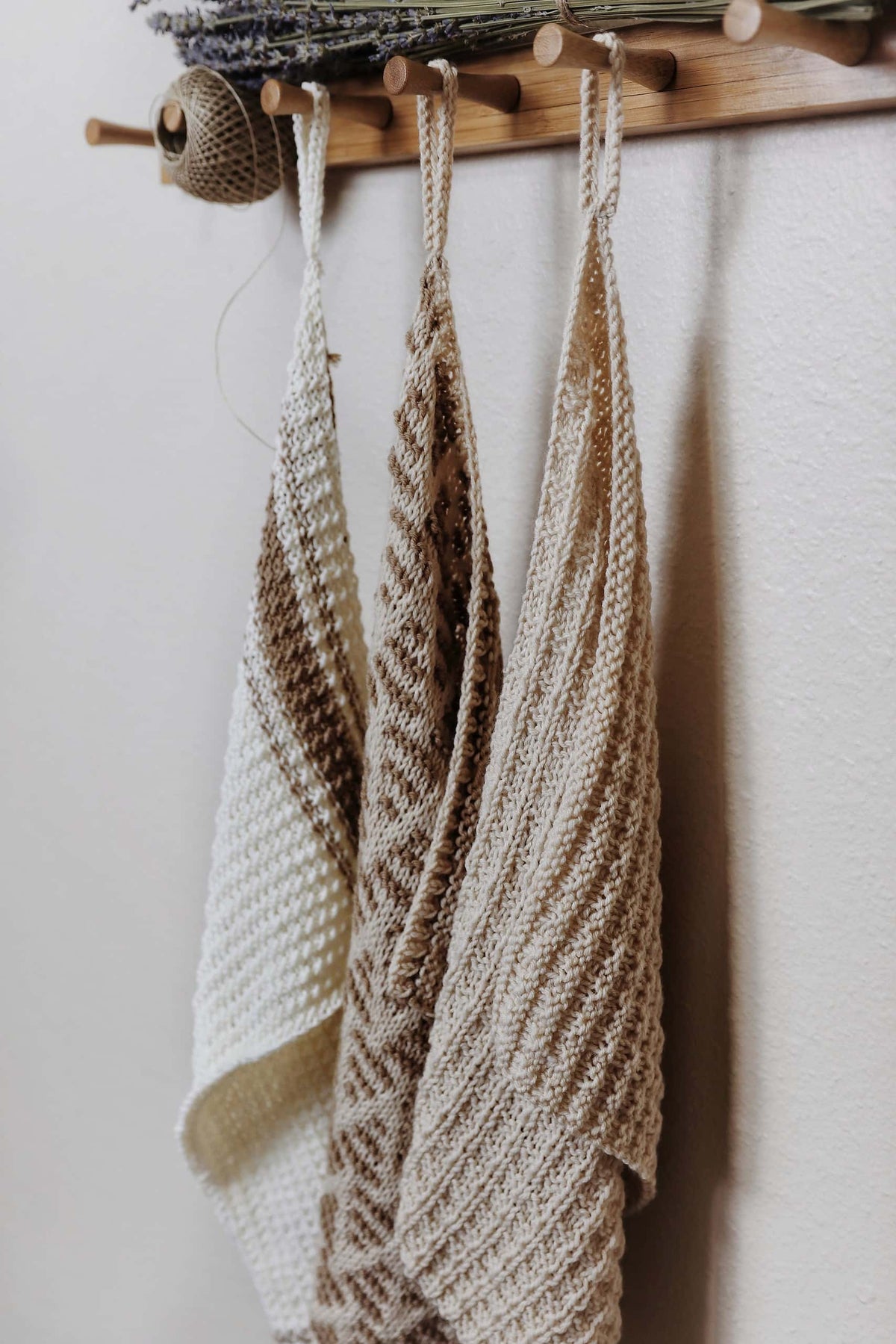 Hand knit kitchen towel with waffle stitch texture draped over wooden chair