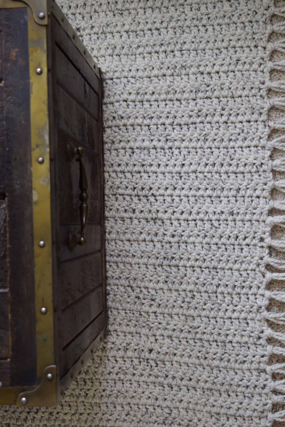 Close-up of handmade crochet area rug showing simple stitch texture and tassel detail