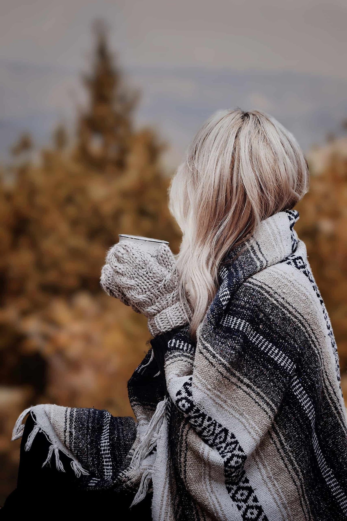 Woman wearing cream cable knit mittens with classic ribbed cuffs