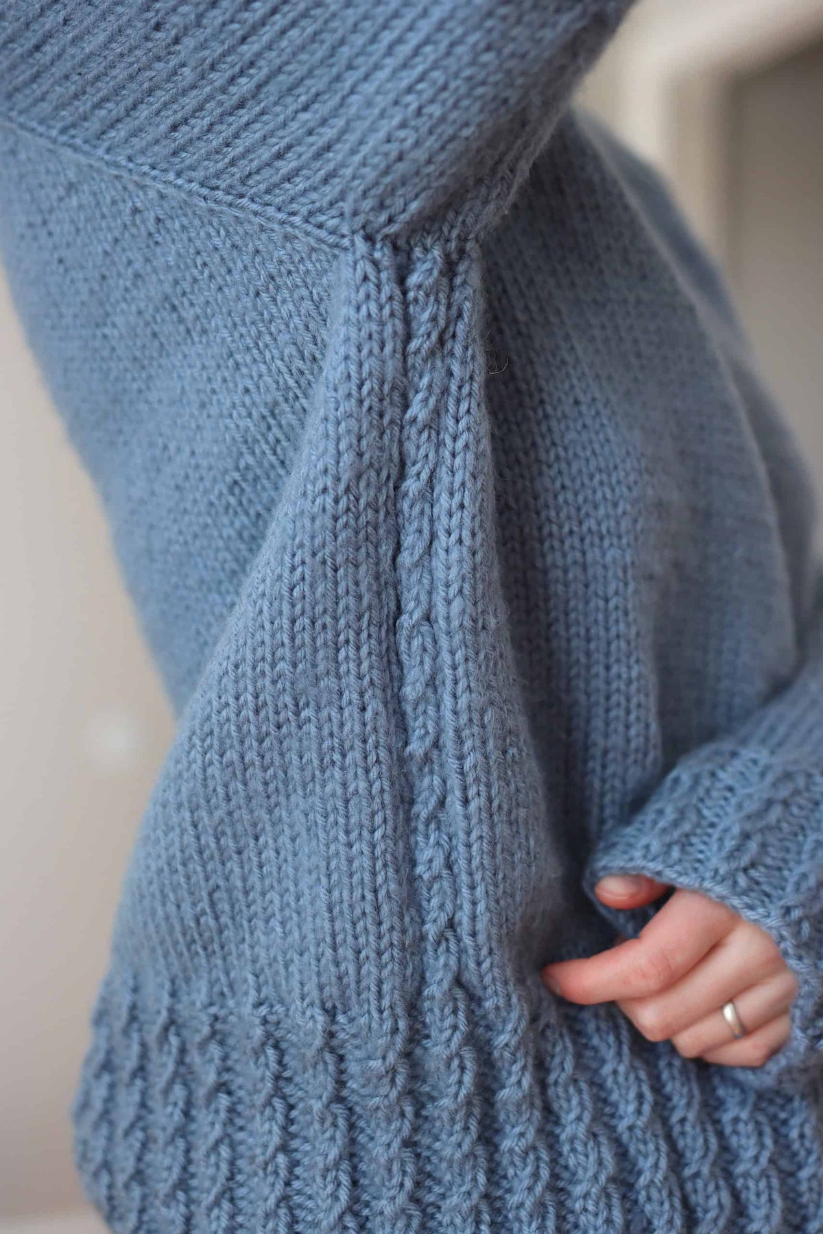 Back view of top-down raglan sweater knitting pattern with cable accents