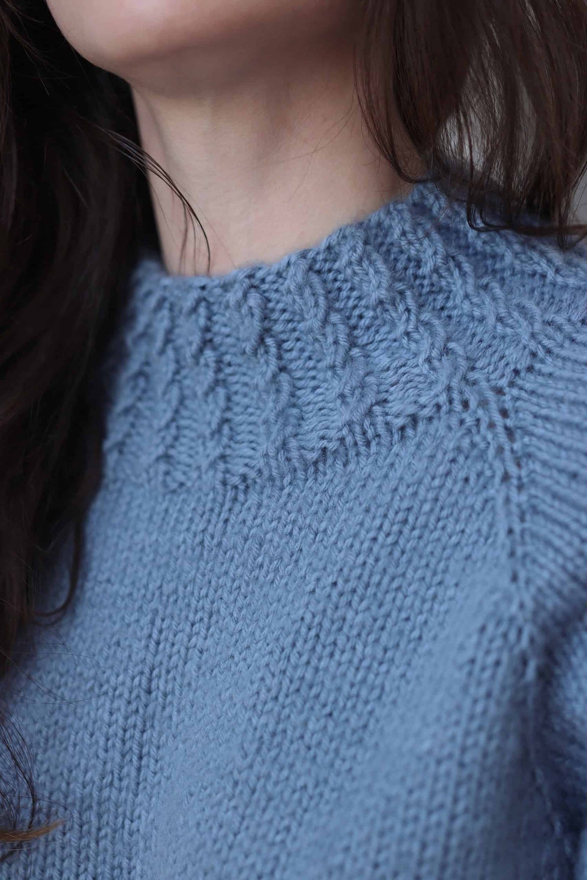 Detail of mock turtleneck and cable knit raglan construction on cream pullover