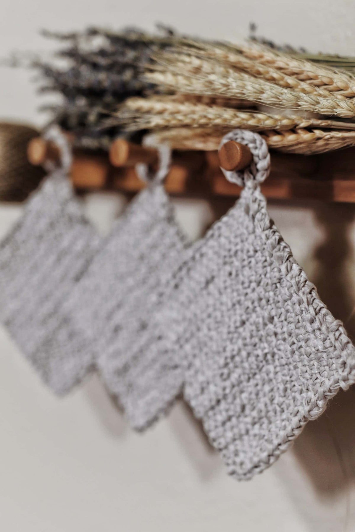 Handknit woven coasters in neutral yarn displayed on wooden table with farmhouse decor