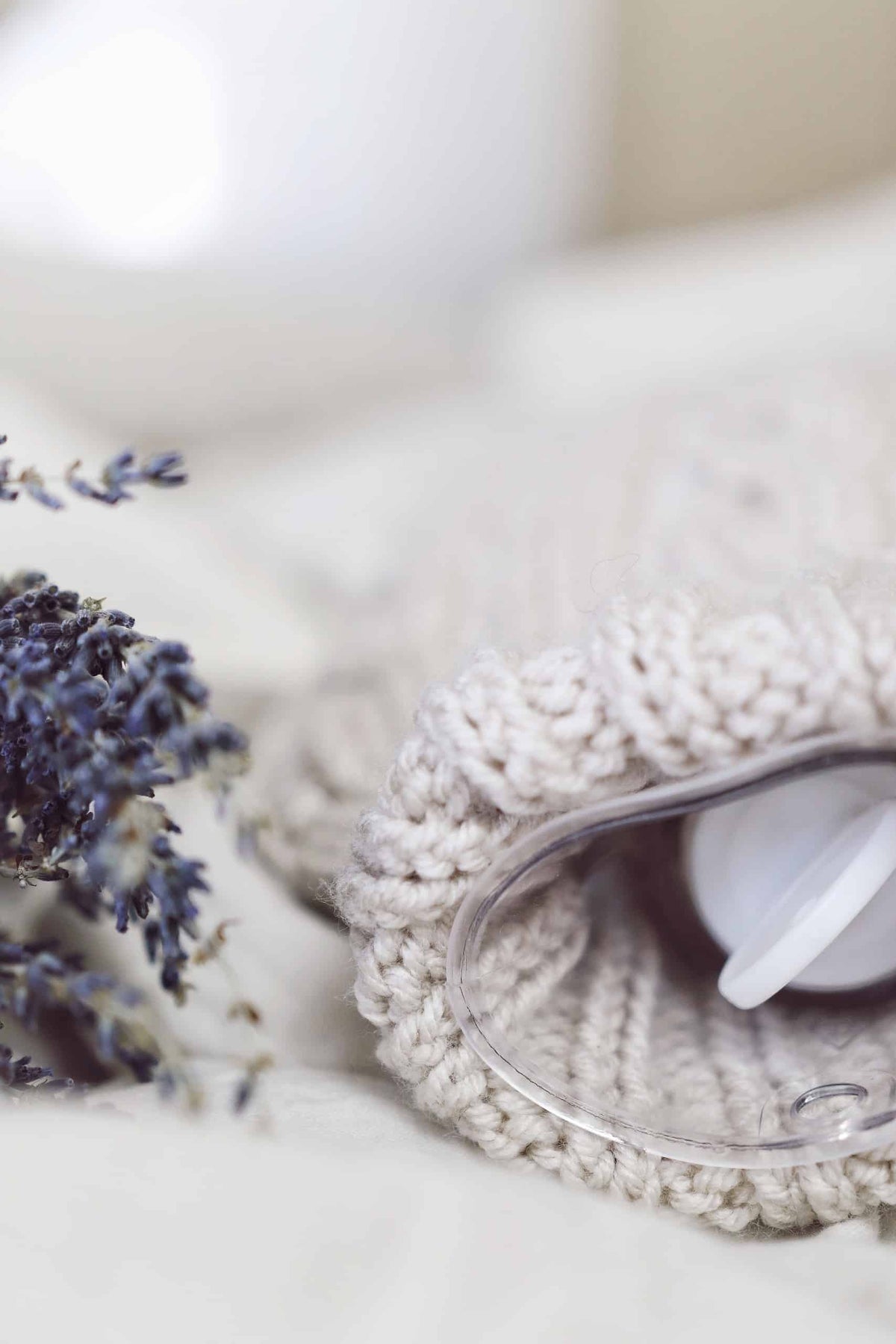 Knitted hot water bottle cover in cream yarn showing classic cable texture and structure