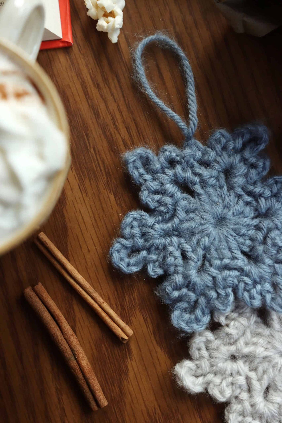 Handmade white crochet snowflake ornament with ribbon hanging on holiday tree