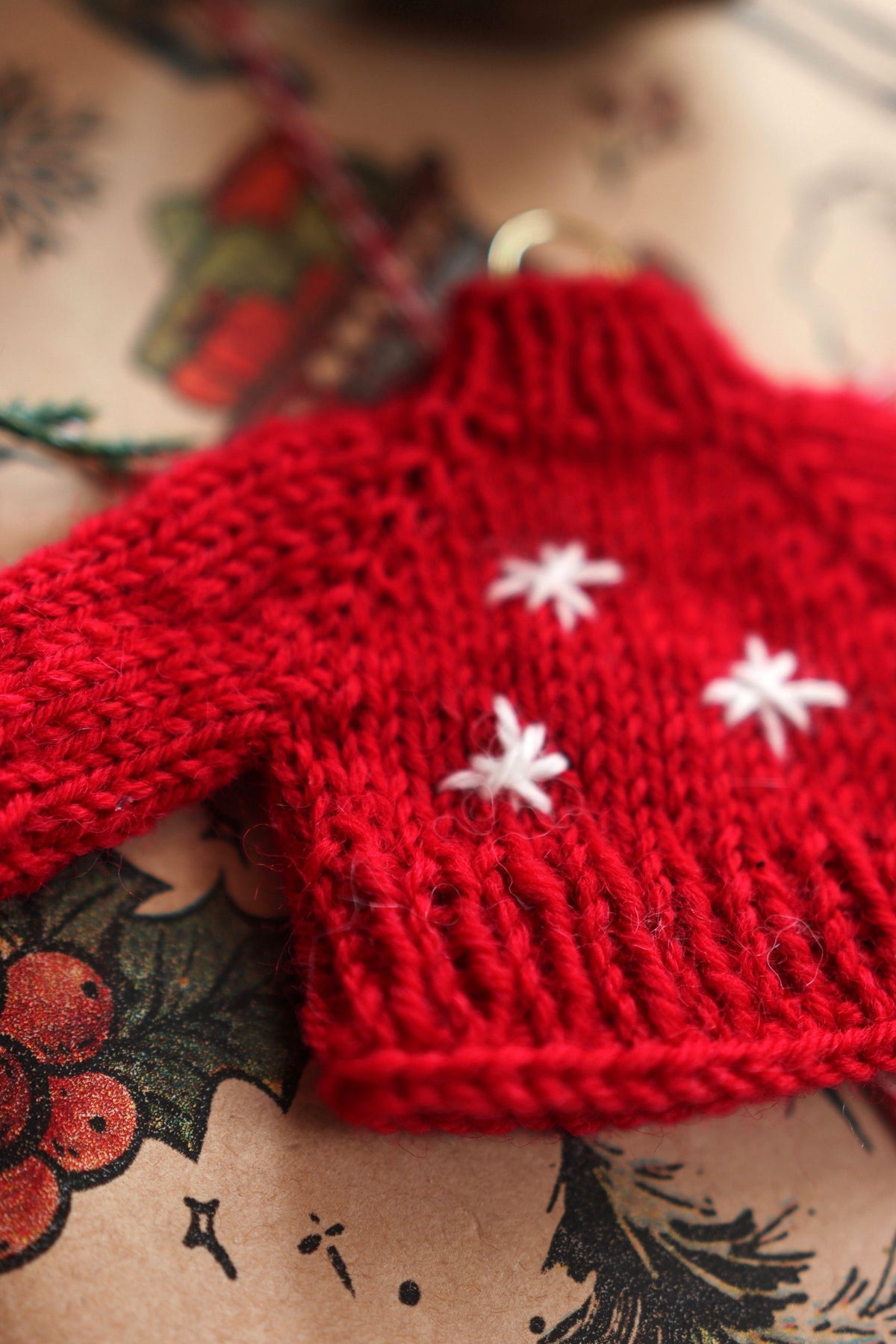 Close-up of tiny raglan knit sweater ornament showing detailed stitchwork and classic design