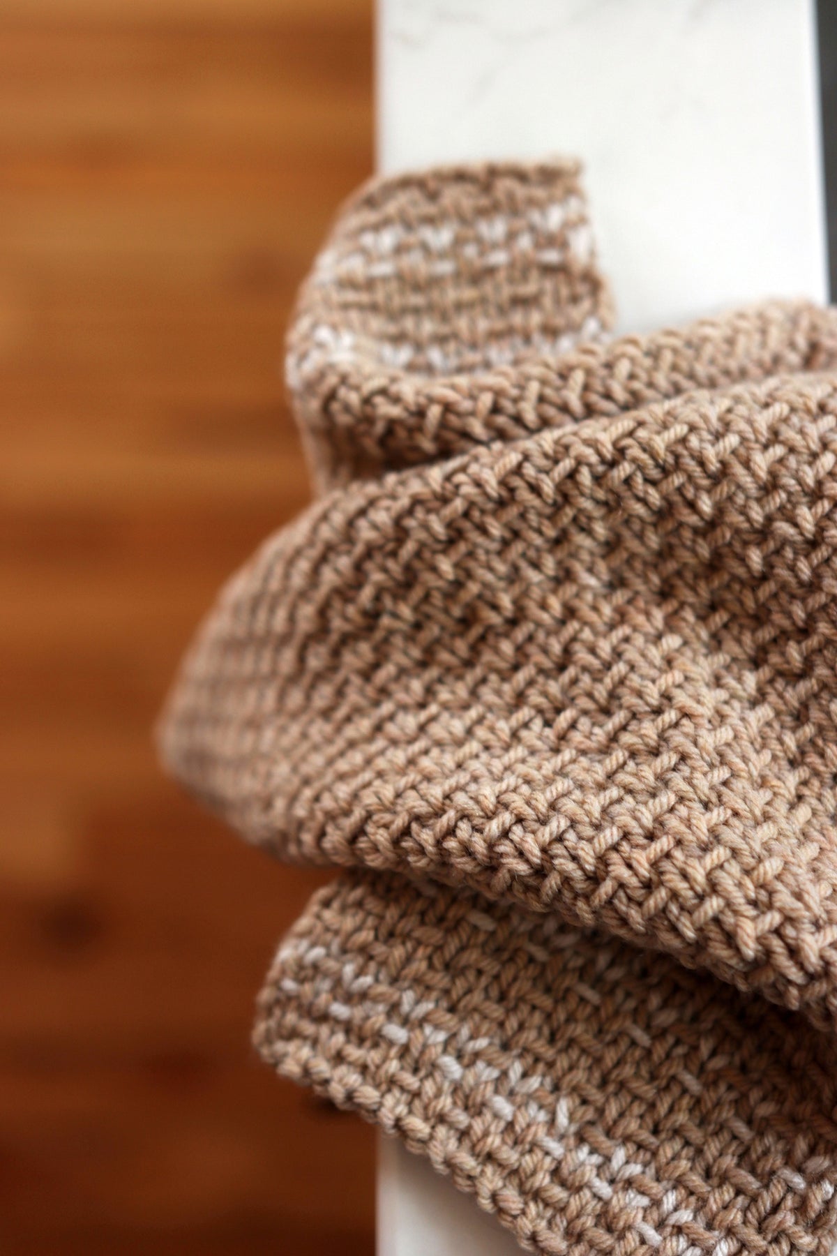 Cream knitted tea towel with textured stitch pattern hanging on wooden hook - Homestead Towel pattern by Darling Jadore