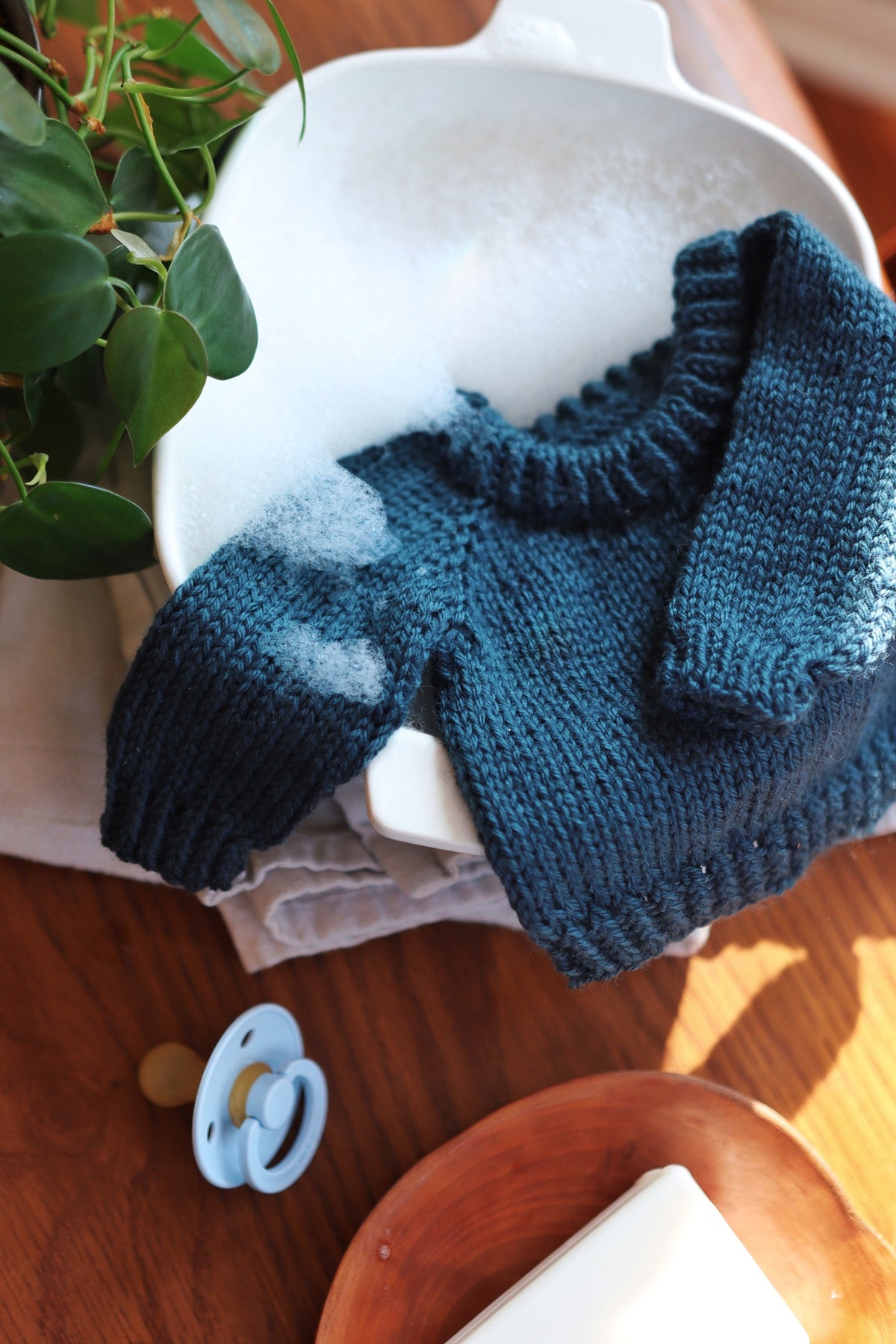 Hand knit baby sweater in cream yarn showing timeless raglan style