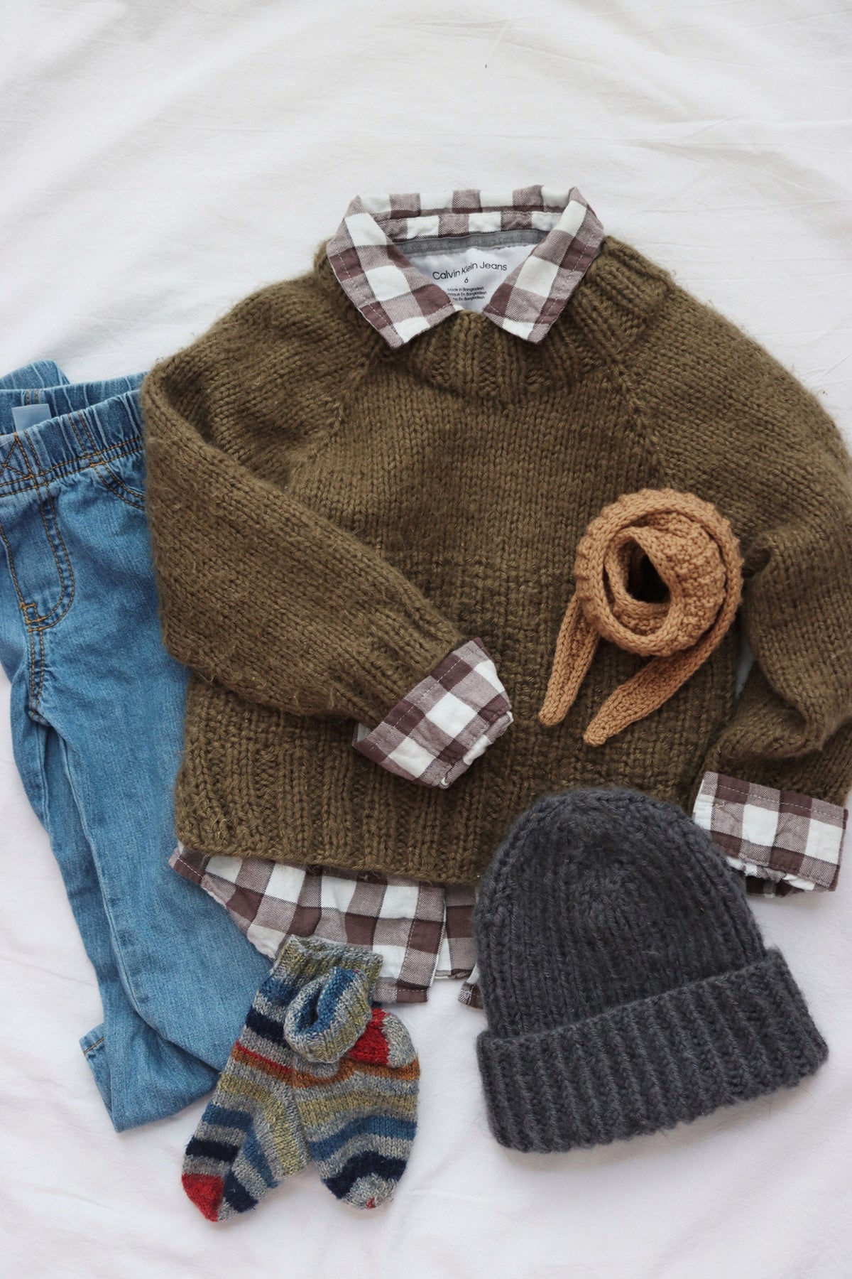 Toddler wearing cream knit beanie with fold-up brim handmade from pattern