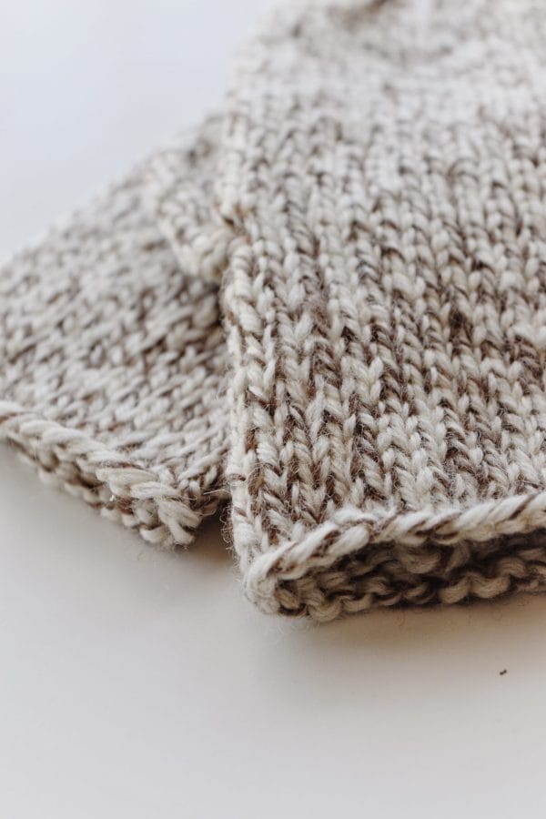 Pair of cream knit mittens flat lay showing timeless stockinette stitch pattern