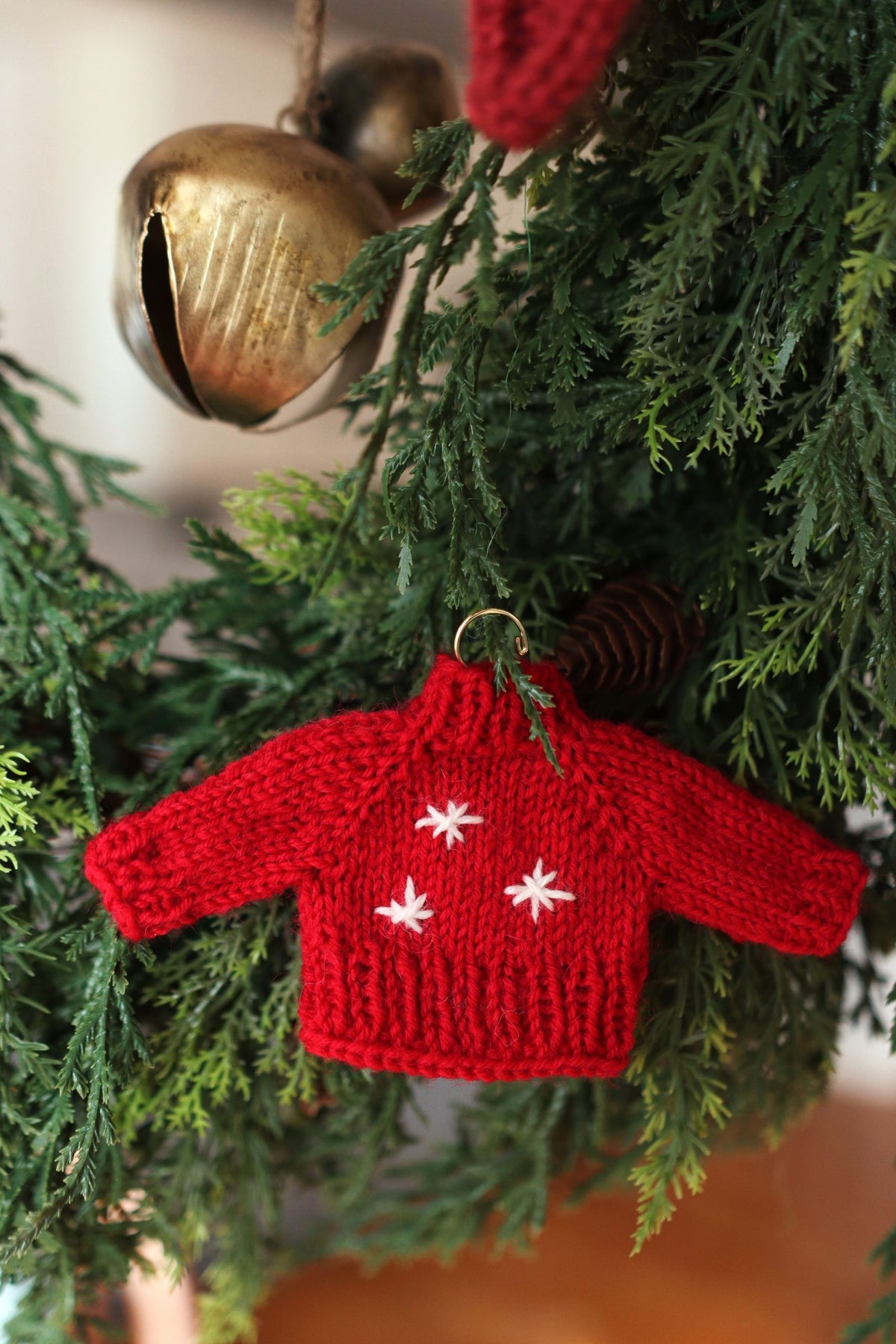 Mini knitted sweater ornament pattern styled with cozy winter aesthetic and natural lighting