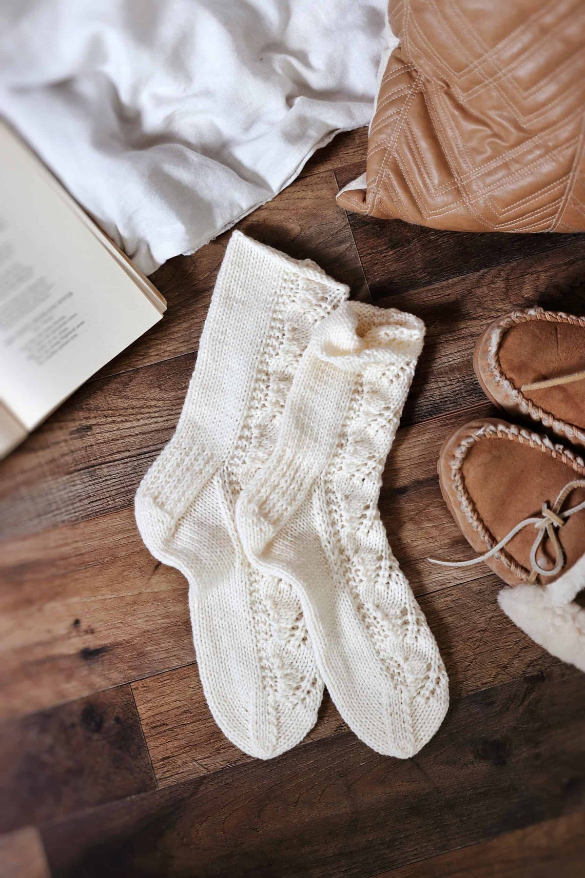 Flat lay of cream lace socks showing full leaf lace knitting pattern