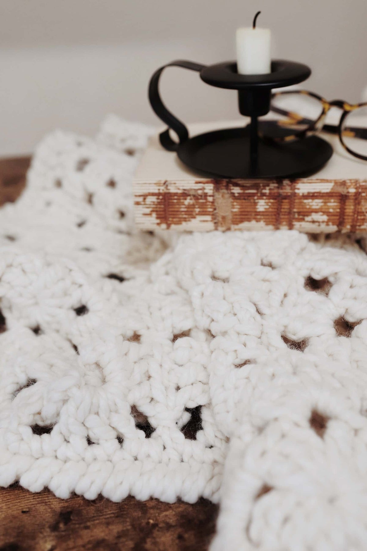 Cozy cream crochet throw blanket styled on modern minimalist sofa - vintage-inspired granny square design