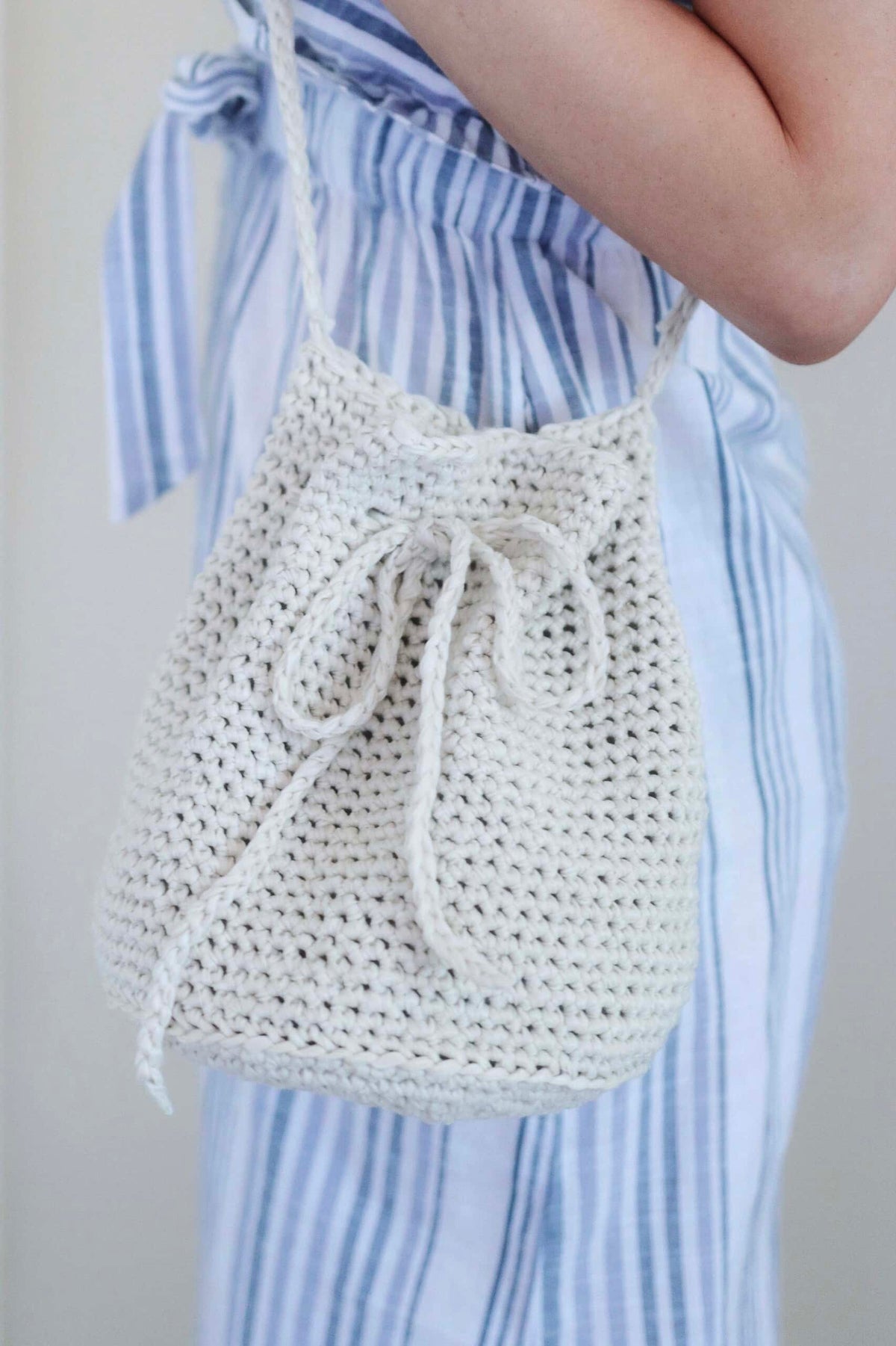 Handmade crochet bucket bag in cream yarn showing textured stitch detail and leather strap