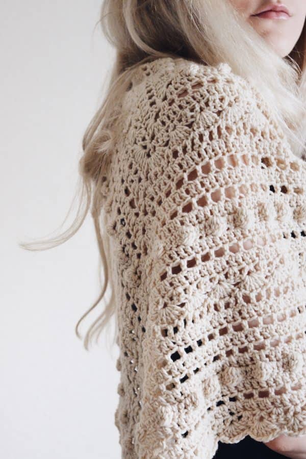 Elegant cream triangle scarf draped showing delicate lace crochet work and bobble details