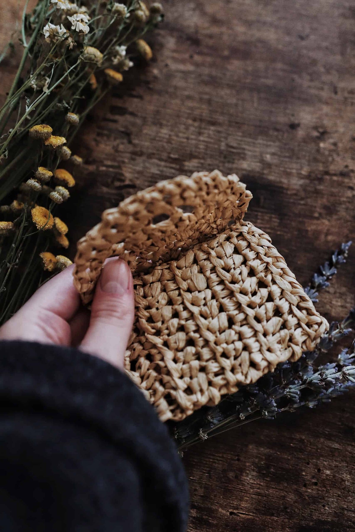 Side view of crocheted raffia coin purse with button closure and delicate lace edging