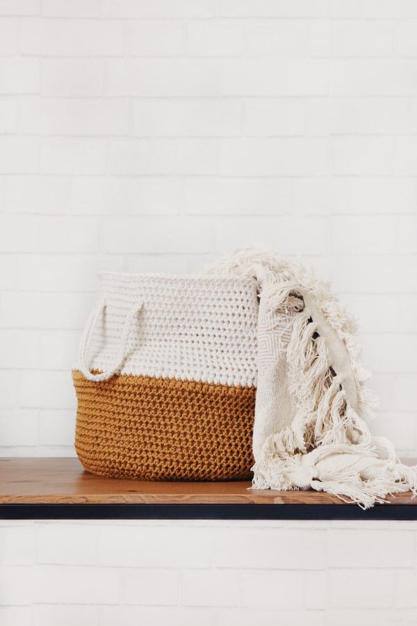 Handmade crochet belly basket in natural fiber with handles displayed on white surface