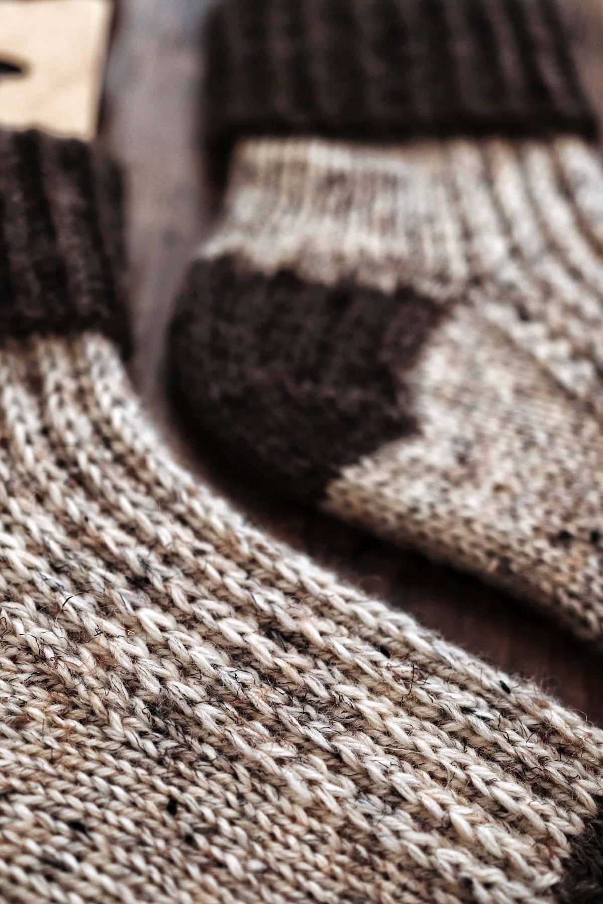 Woman wearing cream worsted weight knit socks with jeans in cozy cabin setting