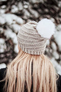 Woman wearing cream Iris beanie with spiral swirl design and faux fur pom pom