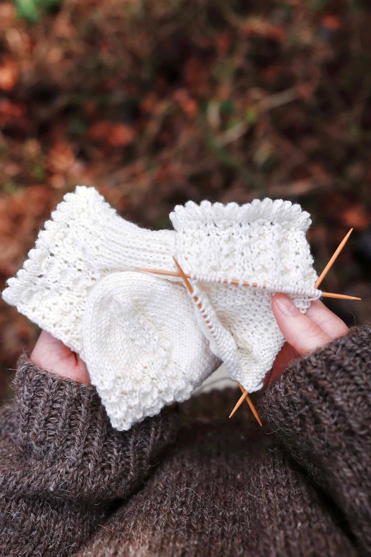 Hand knit lace socks with rosehip motif in natural light setting