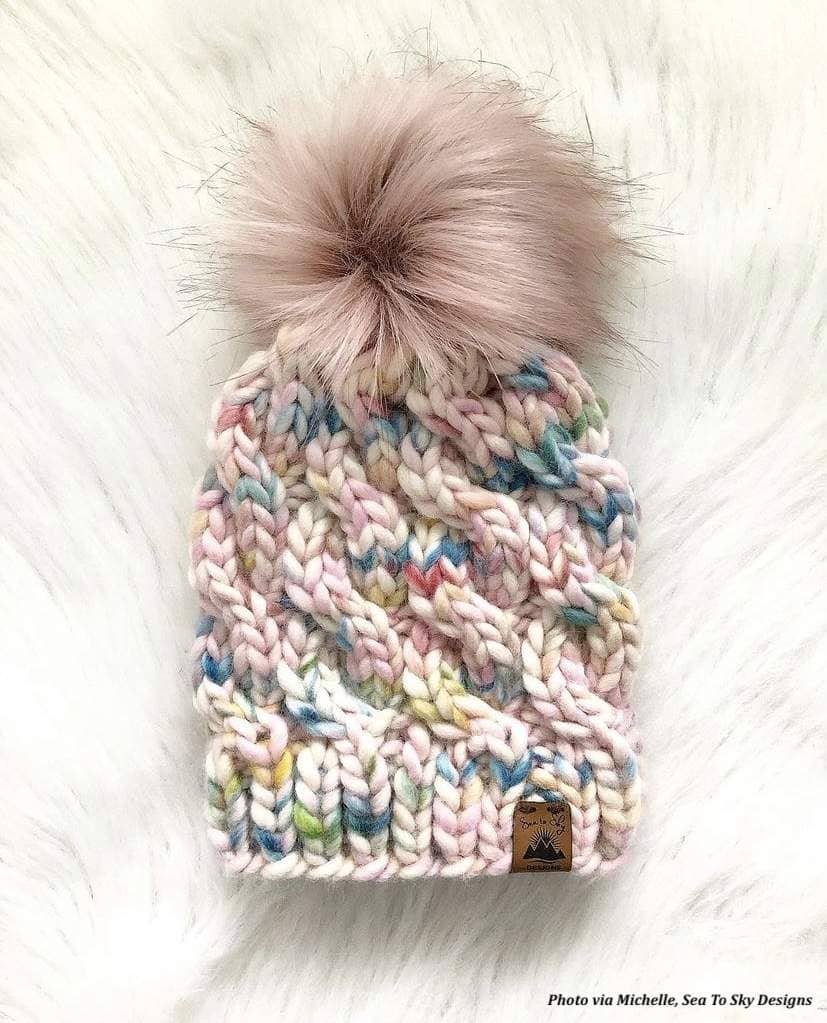Woman modeling Avalon cable knit beanie pattern in natural winter light