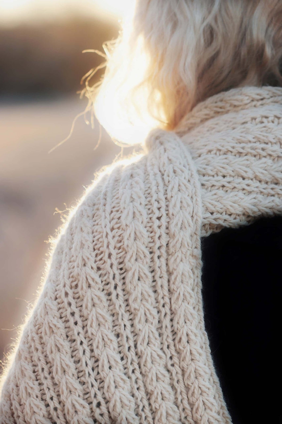 Woman wearing chunky Windchill knit scarf wrapped around neck in winter setting