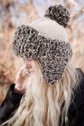 Woman wearing cream faux fur trapper hat with earflaps - The Tundra Hat knitting pattern by Darling Jadore