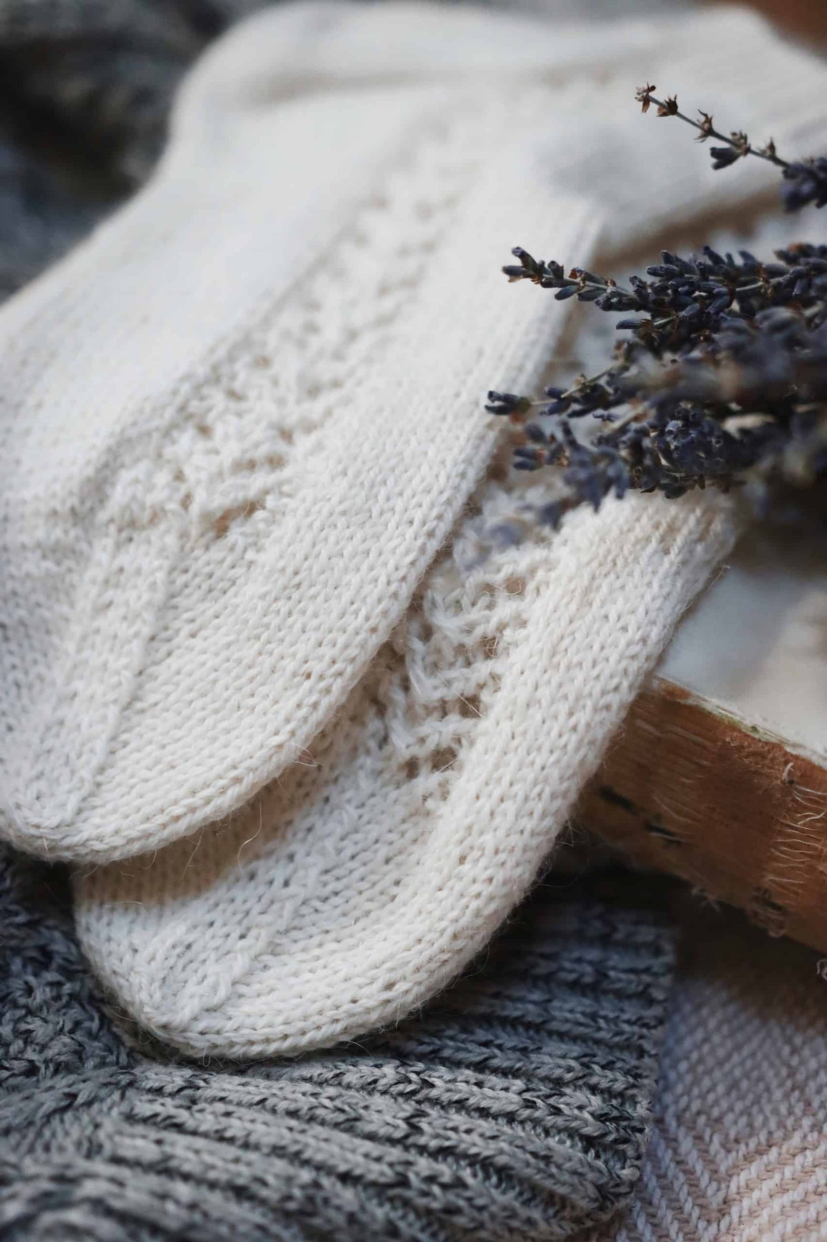 Hand knit Gardenia socks with delicate lace panel in neutral yarn on wooden surface