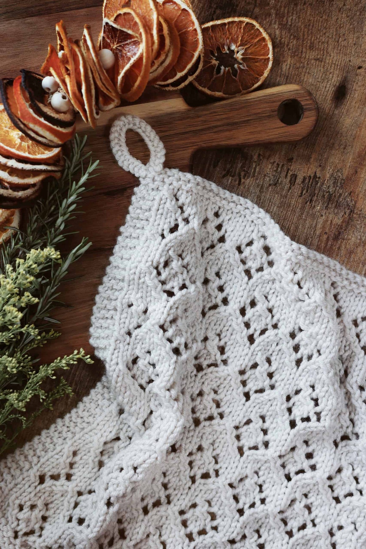 White tea towel with intricate lace knitting pattern displayed on wood