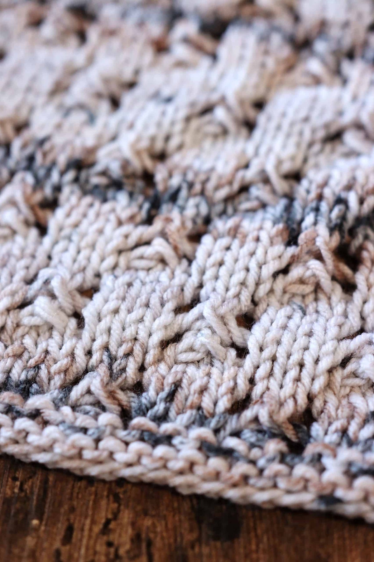 Close-up of lace knit tea towel pattern showing intricate twisted stitch texture and color changes