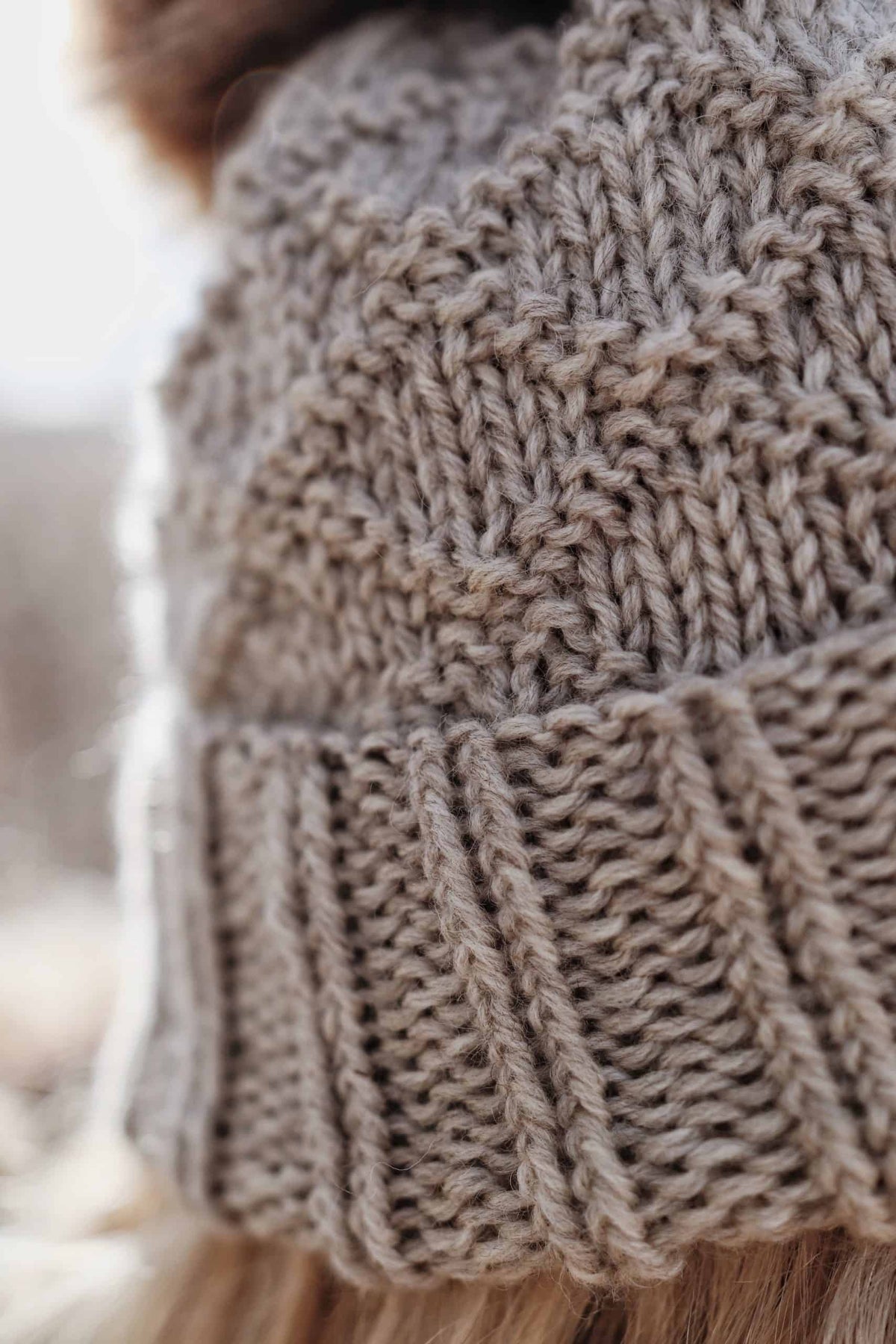 Woman wearing cream Harbor Beanie with diamond motif and pom pom, side view