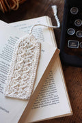 Vintage lace bookmark knitting pattern with swirling delicate design on open book