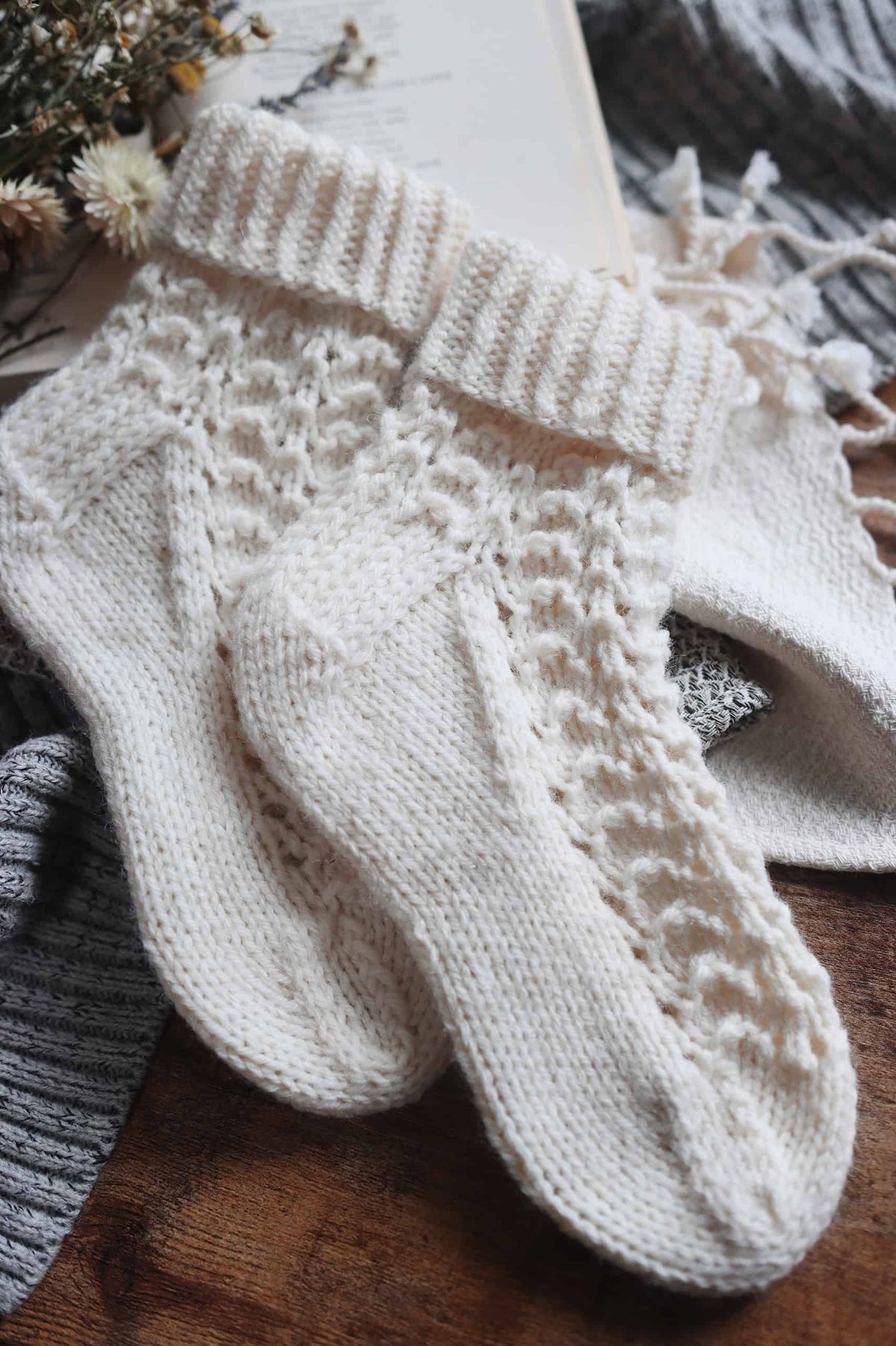 Pair of cream worsted weight hand knit socks with lace cuff detail