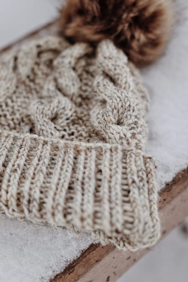 Close-up of cable knit beanie texture showing detailed spiral cable stitches on classic winter hat