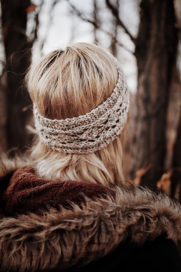 Side view of Phlox lace earwarmer headband knitting pattern worn as winter accessory