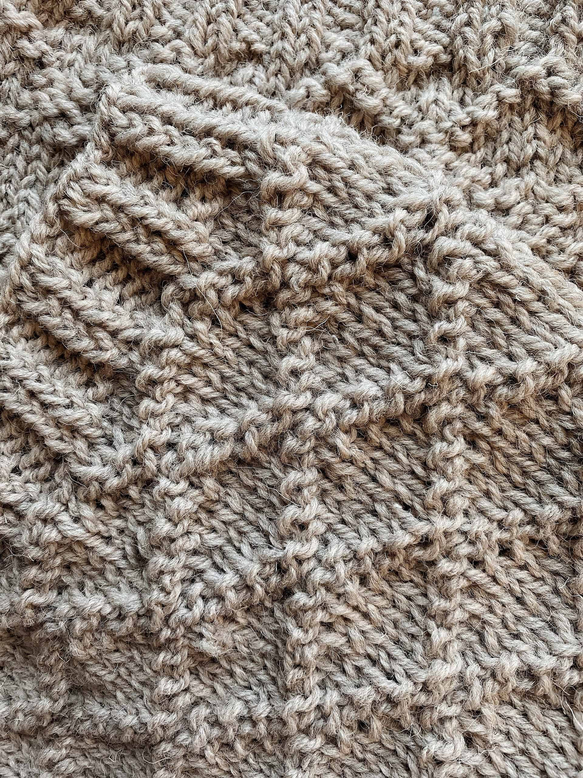 Close up of textured diamond stitch pattern on The Harbor Cowl knit in natural wool