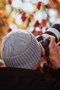 Classic men's beanie knitting pattern in neutral yarn worn by model outdoors
