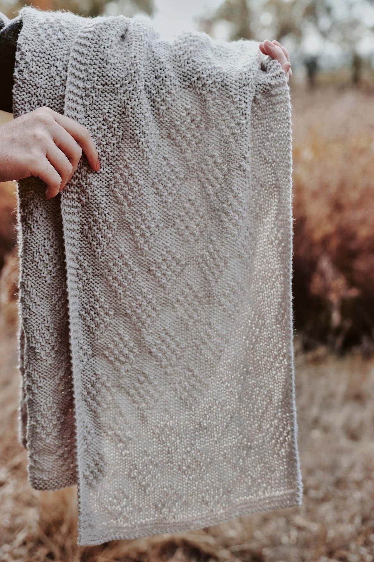 Cream knitted wrap scarf draped elegantly showing textured stitch detail - Estes Scarf pattern by Darling Jadore