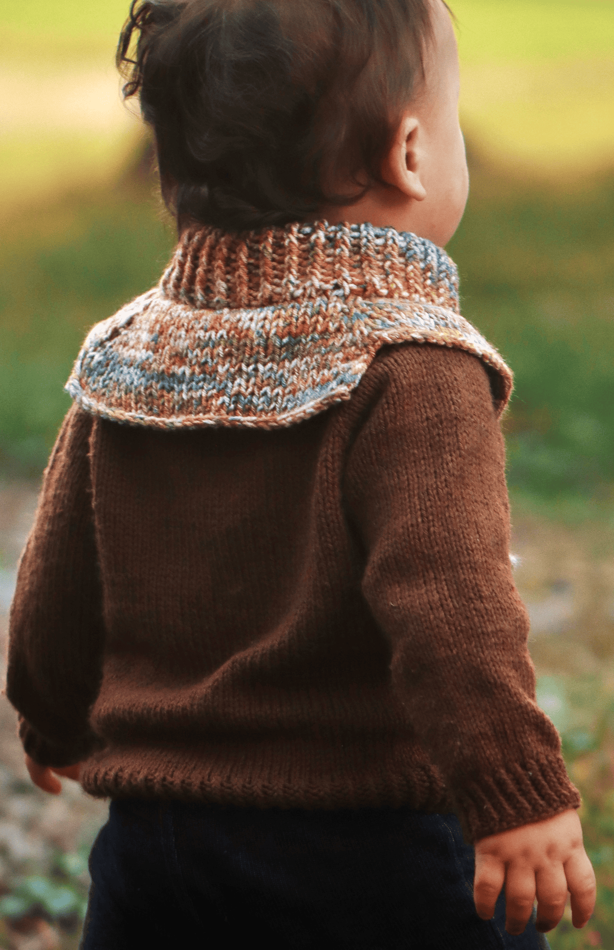 Side view of knitted toddler dickey showing ribbed neckline and button closure