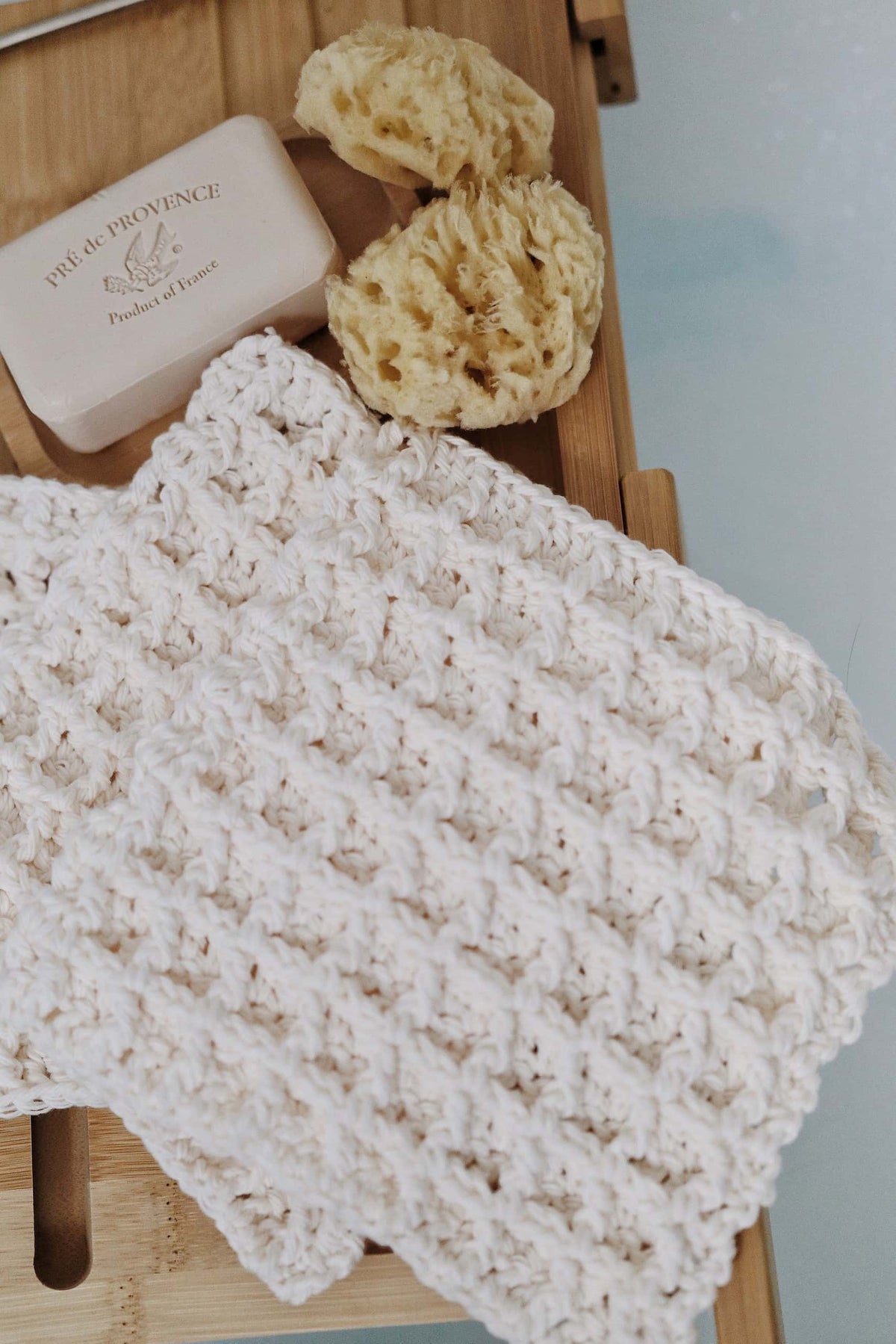 Stack of handmade crochet wash cloths in white cotton displaying textured exfoliating surface